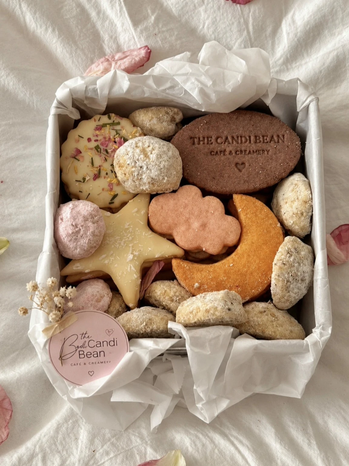 Assorted Candi Bean cookie gift box with star, moon, flower, and bite-size cookies wrapped in white tissue paper